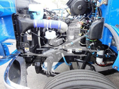 Peterbilt 337 engine bay in a rollback truck showing cooling system, turbo hose, air filter, battery, and hydraulic components.