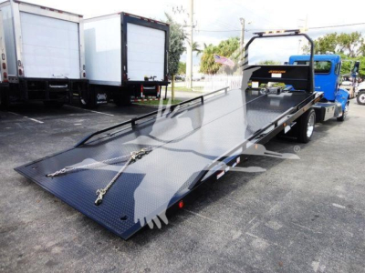 Peterbilt 337 rollback truck with a large flatbed incline in a dealership lot.