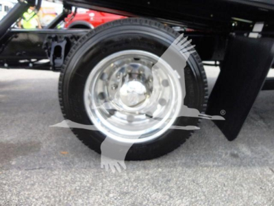 Peterbilt 337 rollback truck wheel and tire close-up showing polished chrome rim and black tire underframe.