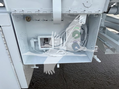 Trailer component panel showing electrical box and coiled hoses with green and purple reels inside a light gray enclosure.