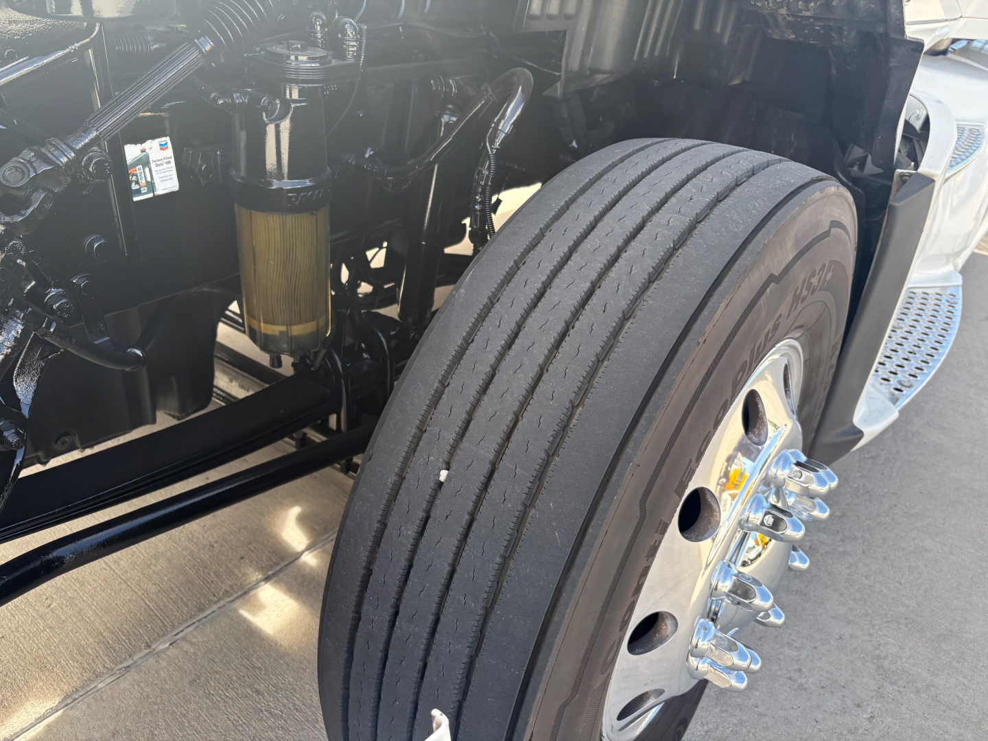 Kenworth T680 wheel and front suspension area showing large steer tire and front axle components.