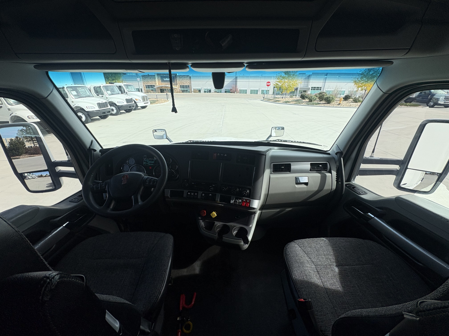 Kenworth T680 interior view through windshield showing dash, steering wheel, and front seats.