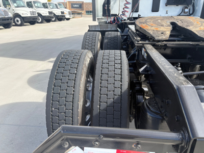 Kenworth T680 chassis with dual rear axles and tires visible; partial cab and frame at a dealership lot.