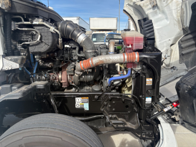 Kenworth T680 engine bay showing turbocharger, intake hoses, coolant reservoir, and various cables; view from open hood.