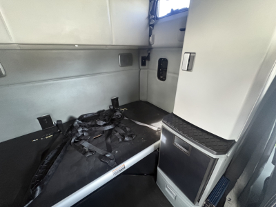 Kenworth T680 truck cab interior sleeper area with seatbelts and storage cabinet visible.