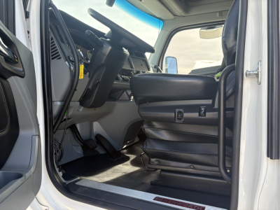 Kenworth T680 truck interior cabin view from open driver door showing steering wheel, dashboard, and driver's seat with controls.