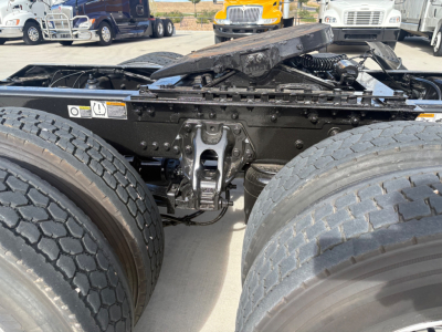 Kenworth T680 tractor rear view showing fifth wheel linkage and dual rear tires, with undercarriage components and suspension visible.