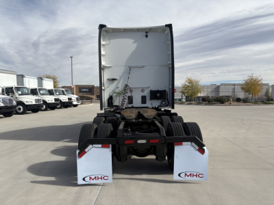 Kenworth truck rear view showing fifth wheel and dual rear axles with mud flaps and white rear skirts, no cargo, bare cab-step area visible.