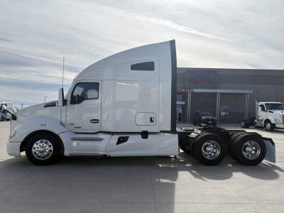Kenworth T680 tractor in white, side view showing sleeper cab, fuel tanks, and rear tandem with dual rear axles; no visible text on image aside from surroundings.