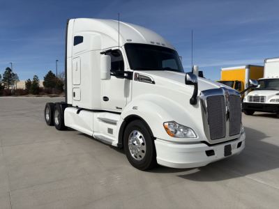 Kenworth T680 truck cab with white paint, front grille, headlights, and side mirrors in a parking lot.