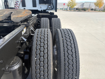Kenworth T680 truck chassis with dual rear axles and fresh tires, partial view of frame and components.