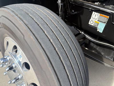 Kenworth T680 wheel and front suspension area showing tire tread lines and wheel hub.