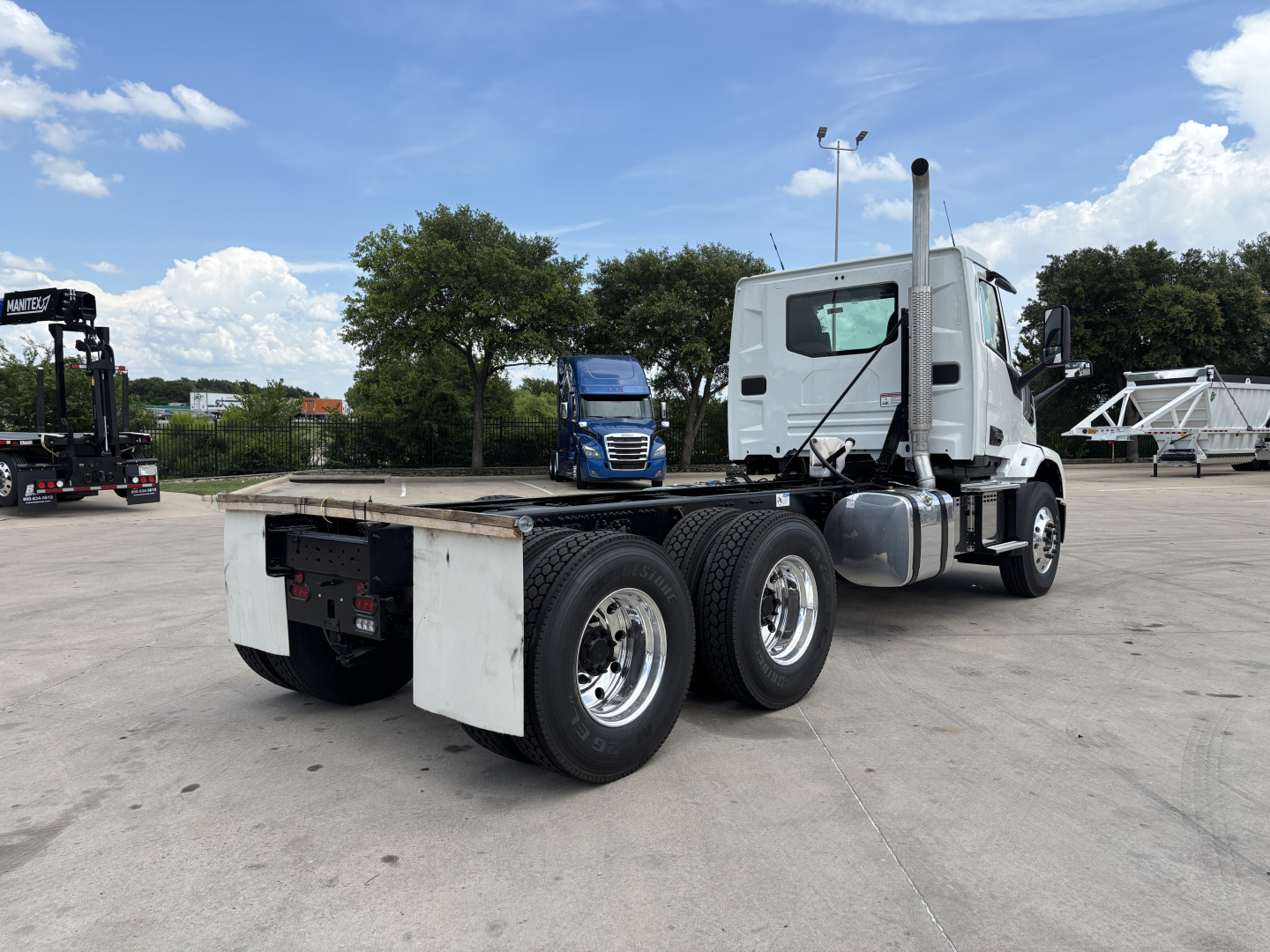 Truck chassis with cab showing rear axles and flatbed, 2027 Mack AN64, side view highlighting dual rear axles and exhaust stack.
