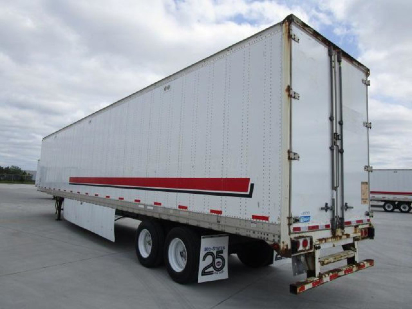 Trailer side view showing 2014 Stoughton van trailer with red and black stripe, tandem rear axles, doors closed, white exterior.