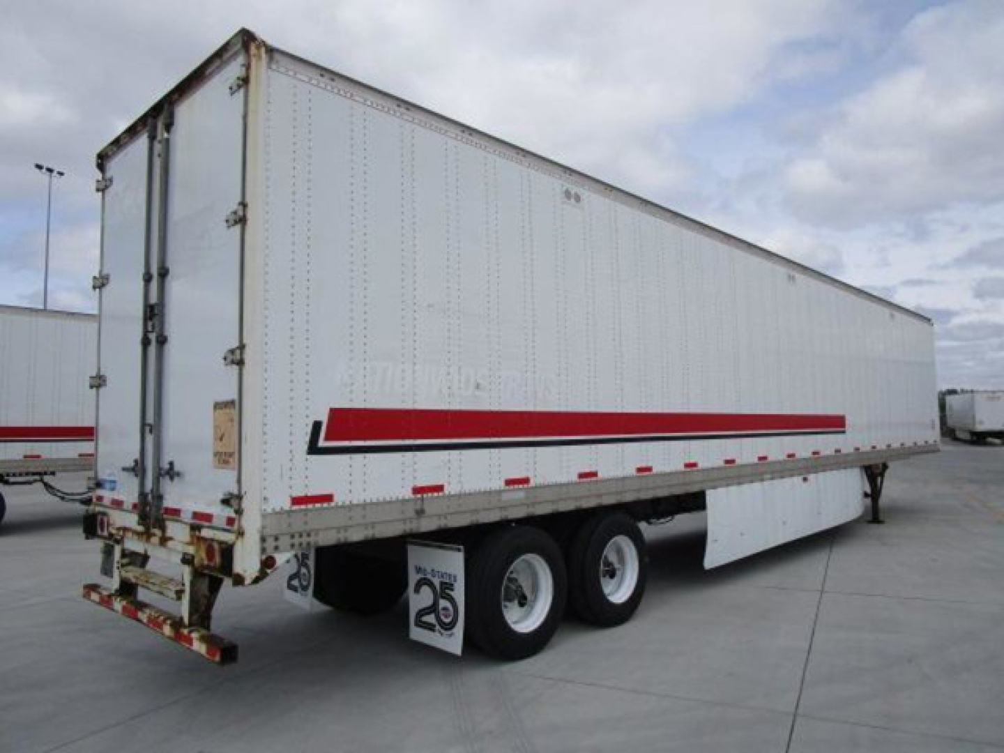 Trailer side view showing a white 2014 Stoughton van trailer with a red/black stripe, triple-axle tandem, rear doors, and registration decals.