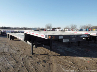 Flatbed trailer showing Fontaine Infinity model in a used stock lot with long deck and ramp legs visible.