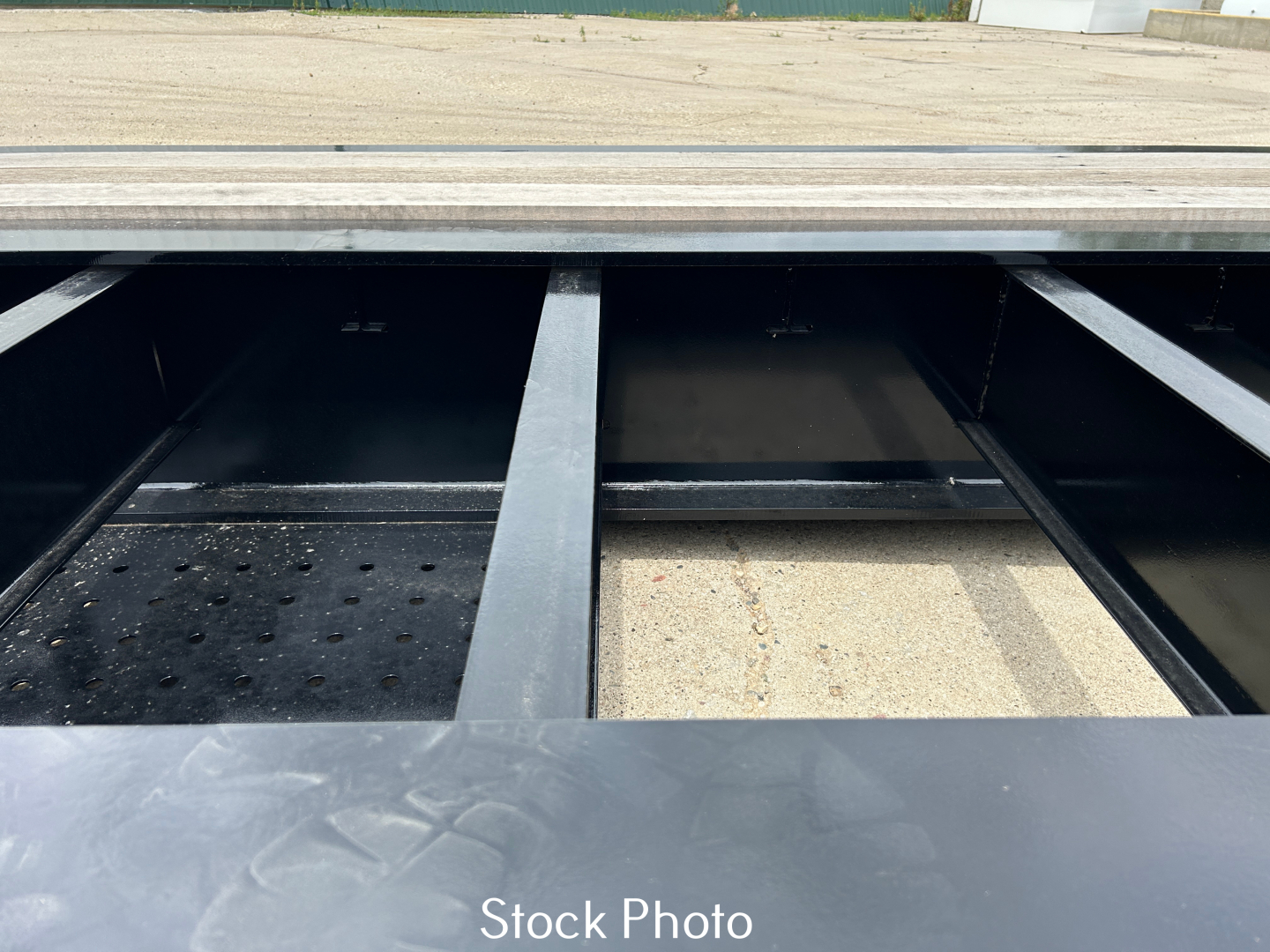 Trailer bed opening showing reinforced metal compartments and storage area on Load King 554-Quad-9' Wide trailer.