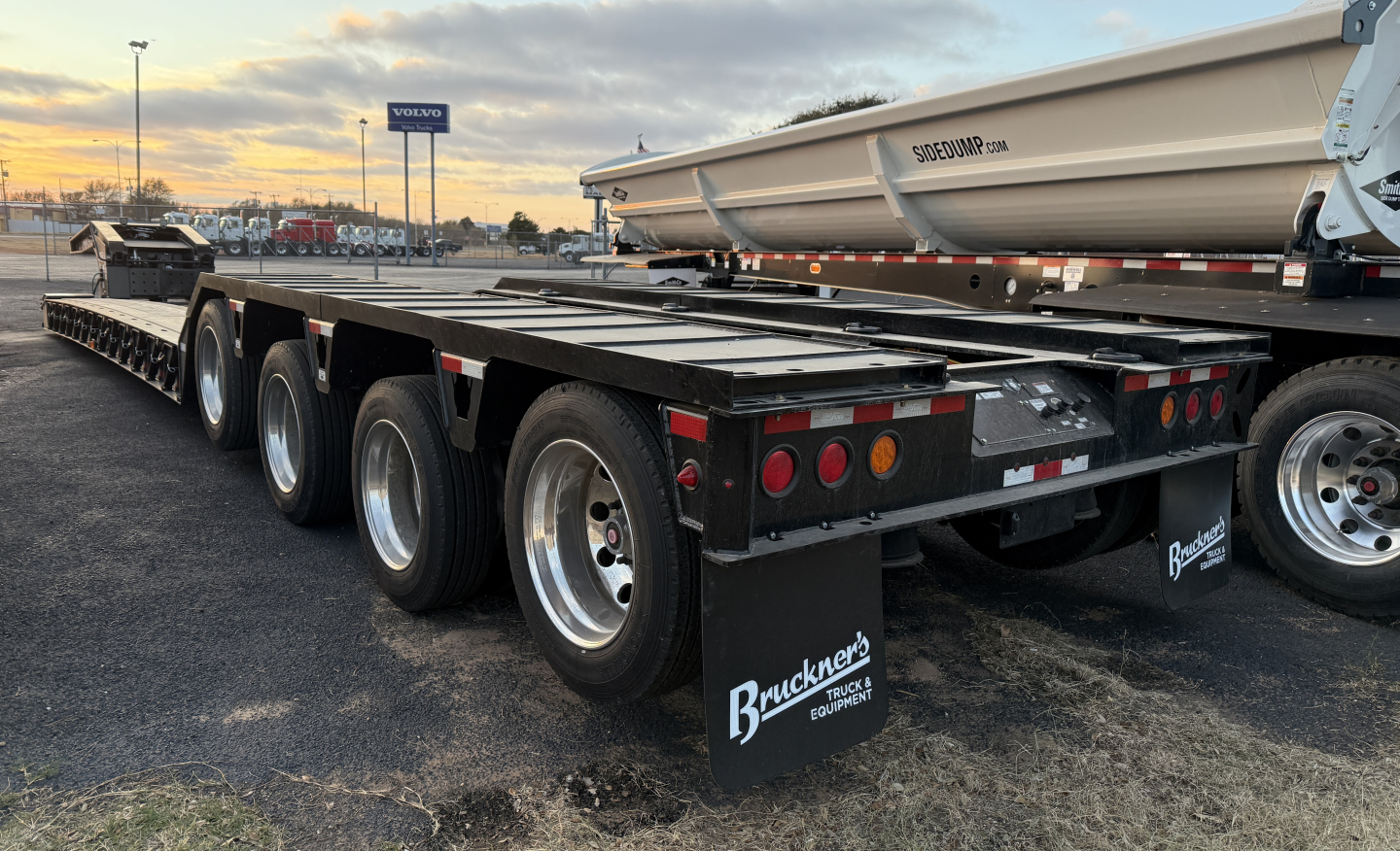 Load King 554-Quad-9' wide 24' LDH lowboy trailer rear view with triple axle configuration and mud flaps showing stock tires and trailer lights.