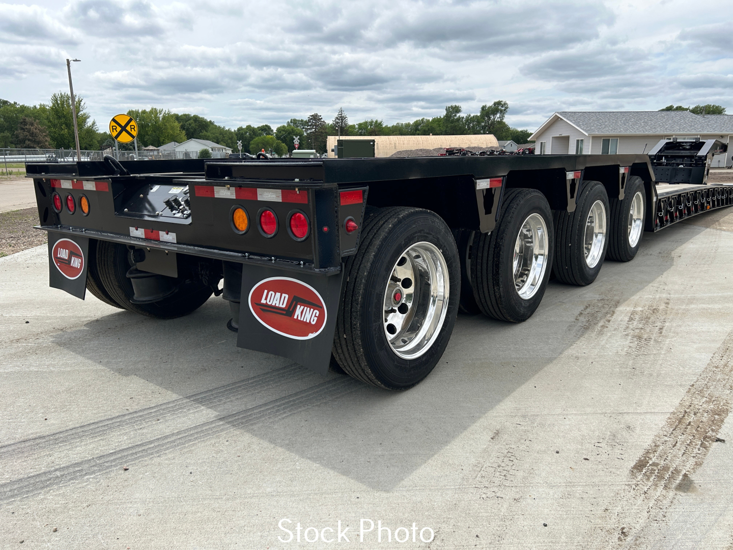 Load King lowboy trailer with multiple axles, rear view showing tires, wheels, and reflective lights; Load King branding on mudflaps; flatbed with LDH features.