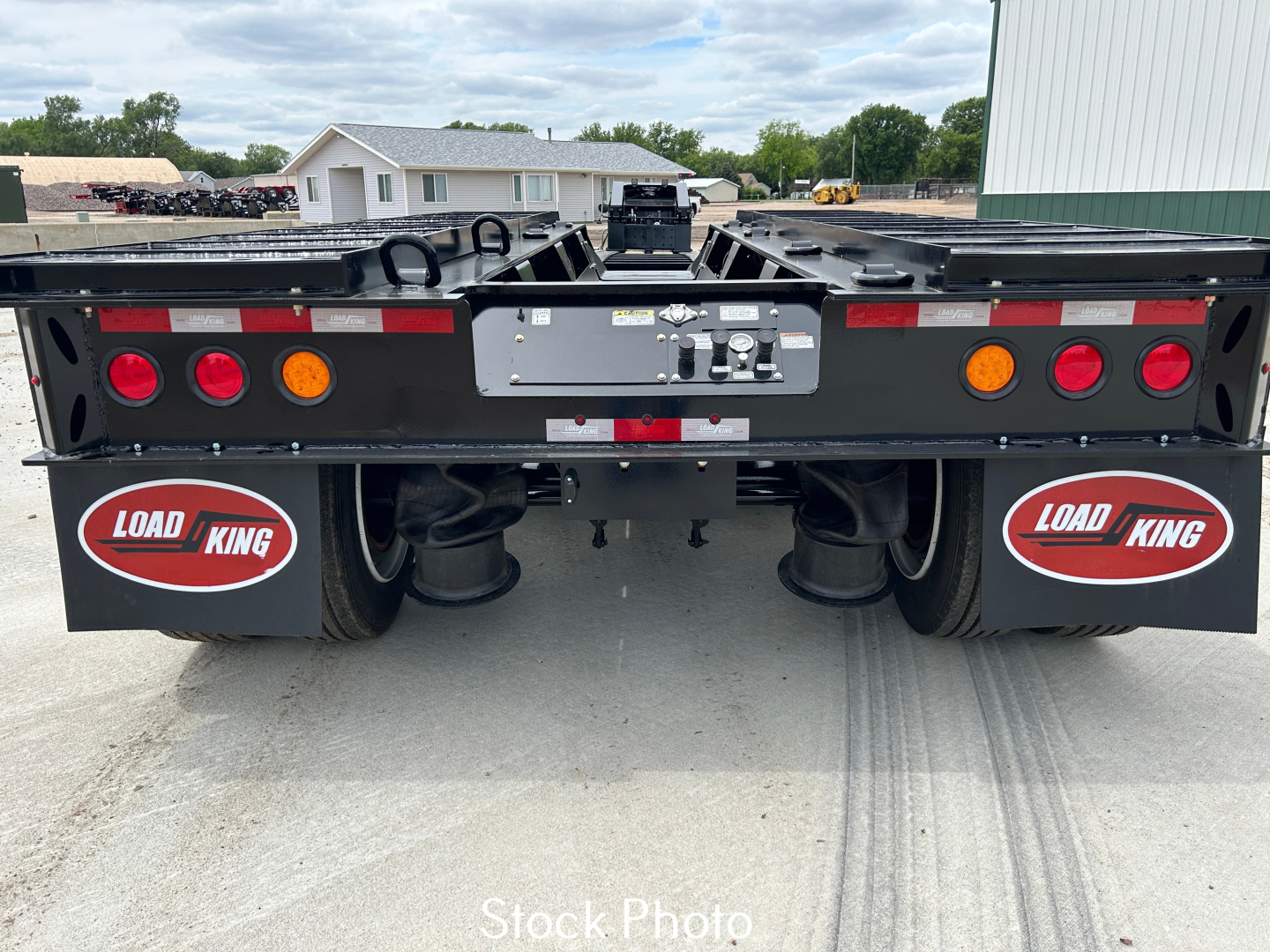 Load King trailer rear view showing black lowboy with dual axles, red oval Load King logos, taillights, and license plate area.