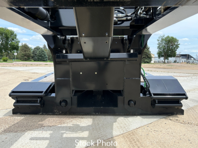 Load King trailer undercarriage showing lowboy with dual tracks and structural center support; visible hydraulics and frame components from front/floor level.