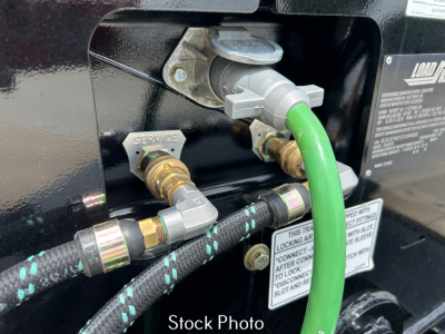 Trailer air line fittings and valves with green hose connected; shows service valves and hydraulic connections on Load King trailer.