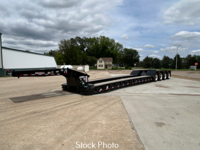 Load King trailer in a parking lot with long lowboy, showing black frame, multiple axles (3/4?) and a gooseneck with step and loading ramps. The image contains a watermark 'Stock Photo' near bottom.