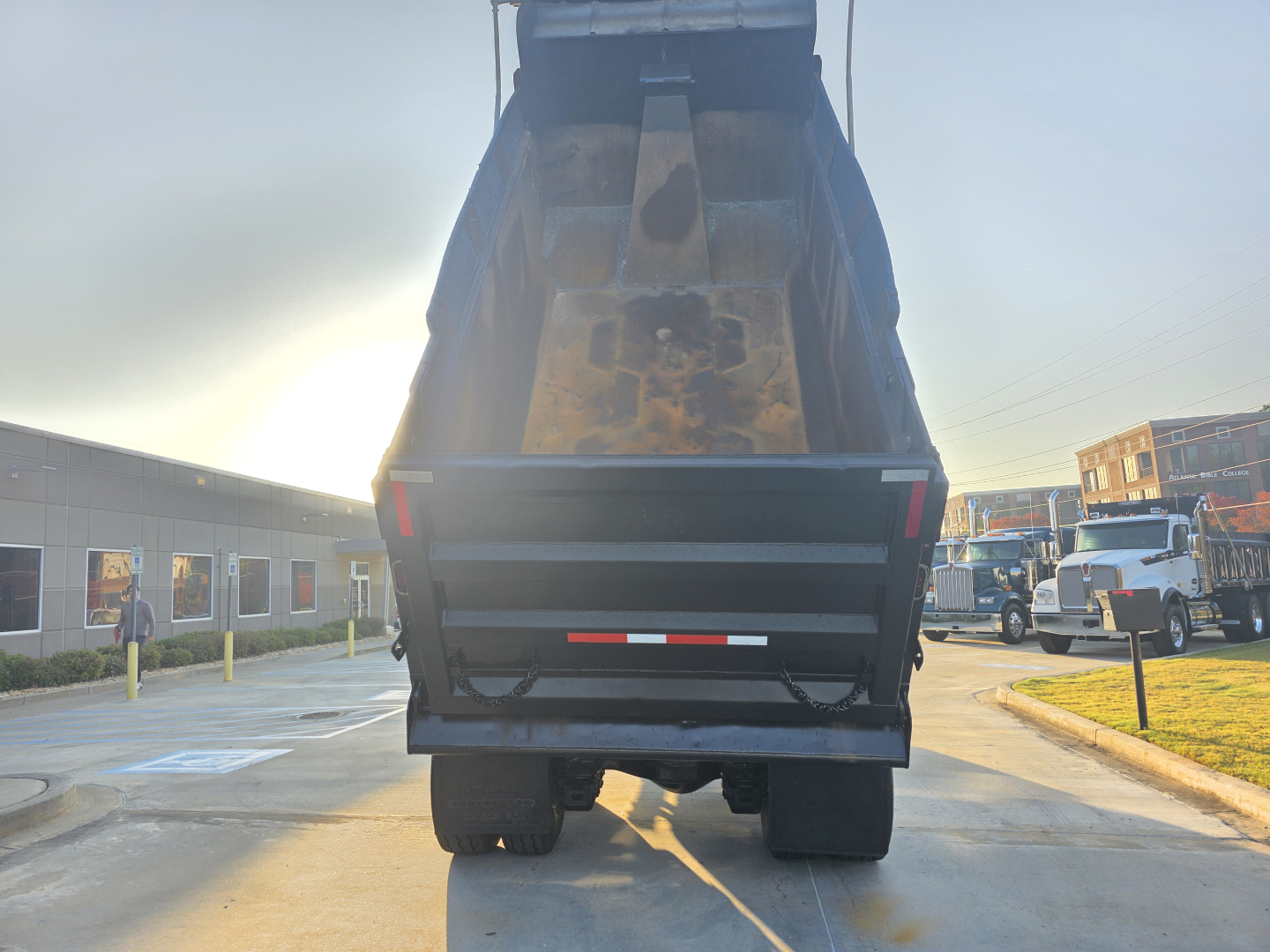Dump truck bed of a 2022 Mack Granite loaded with dirt, rear view showing raised open-box bed and undercarriage.