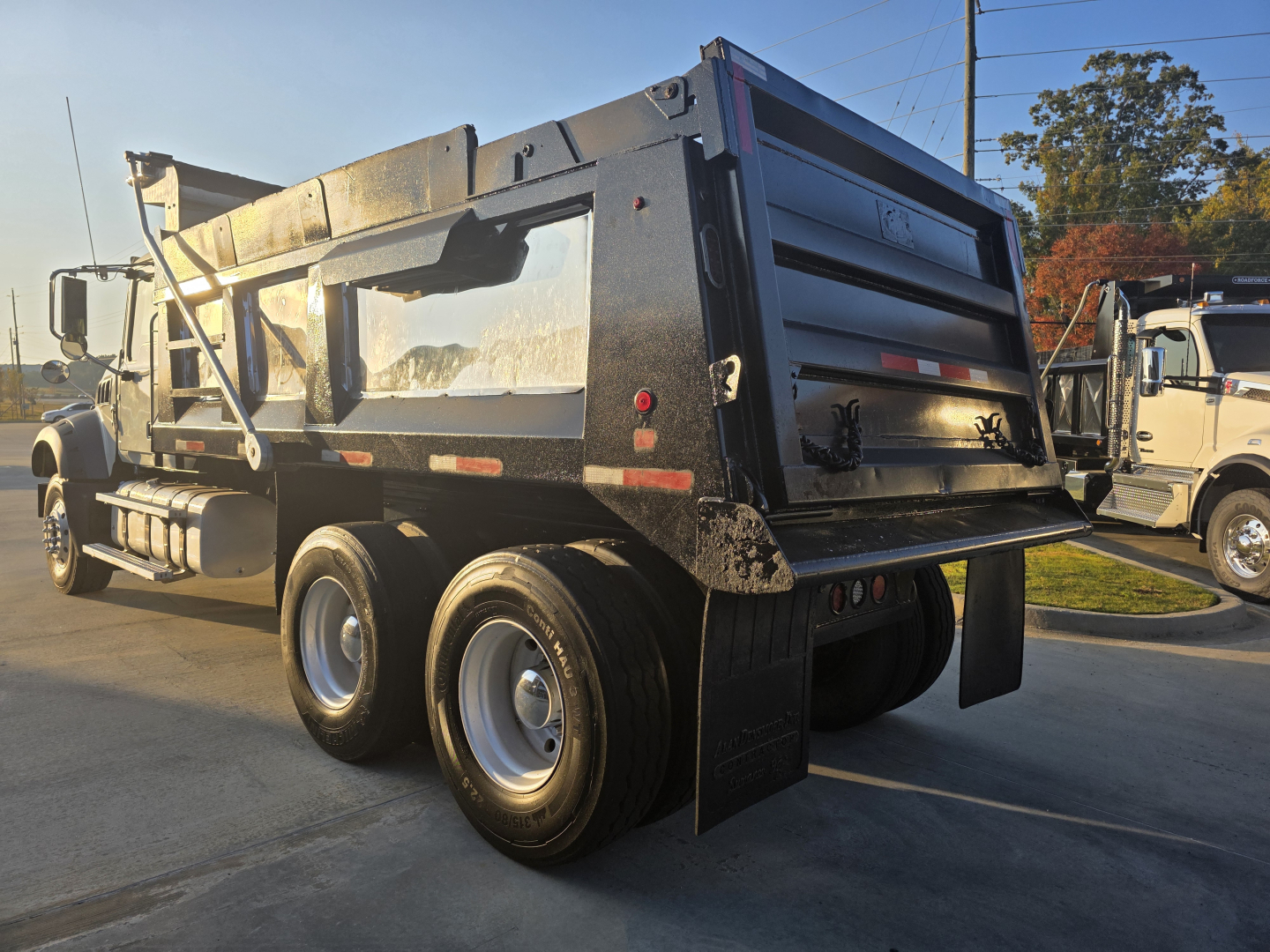 Dump truck rear view showing dual rear axles, black dump bed, and tailgate with reflective red/white striping; Mack Granite 2022 model with VIN 1M2GR2GC6NM025884 (visible on listing).