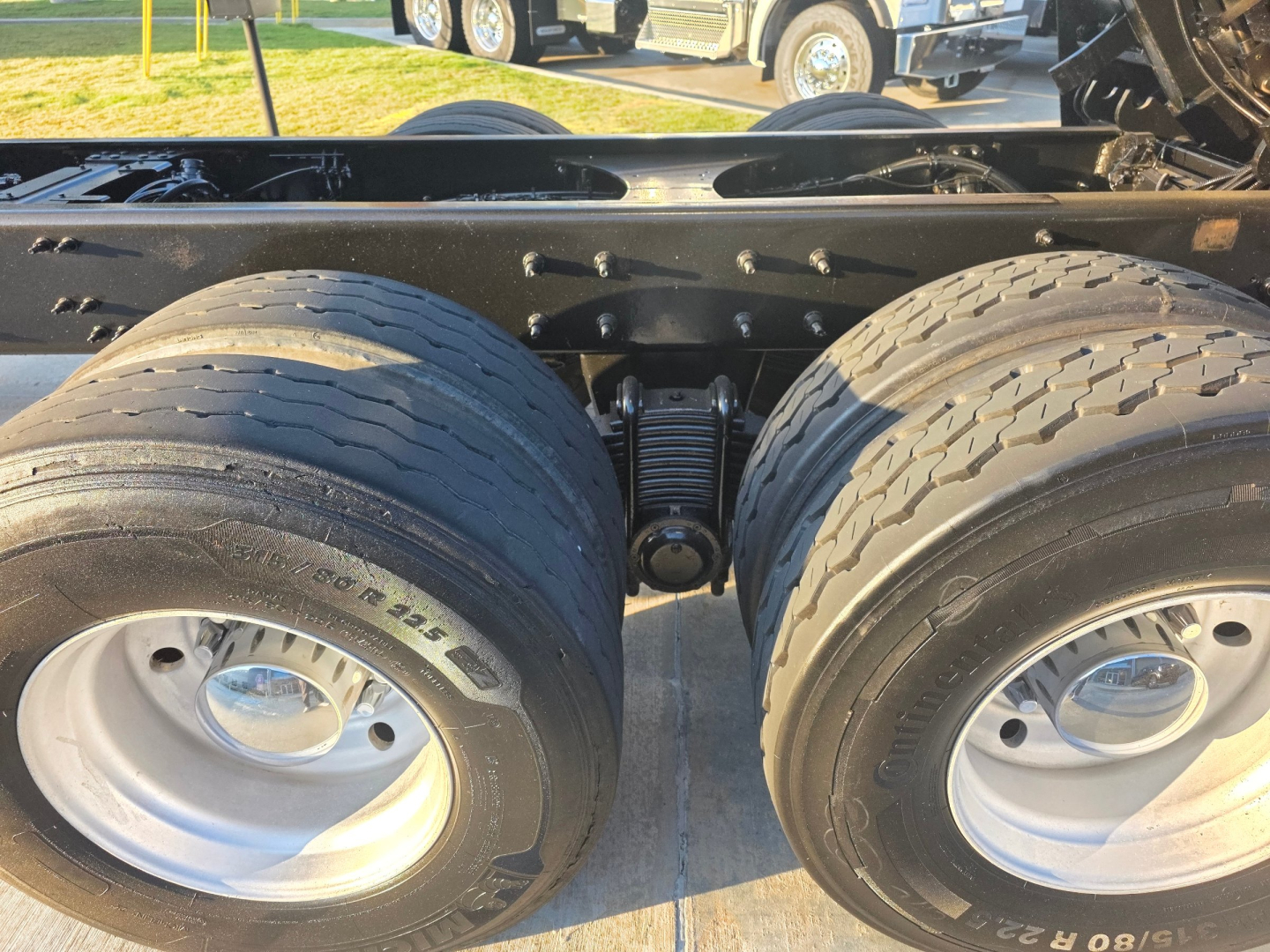 Dual rear truck axles with springs and tires, Mack Granite chassis frame, mounting hardware, and fifth-wheel area visible undercarriage.