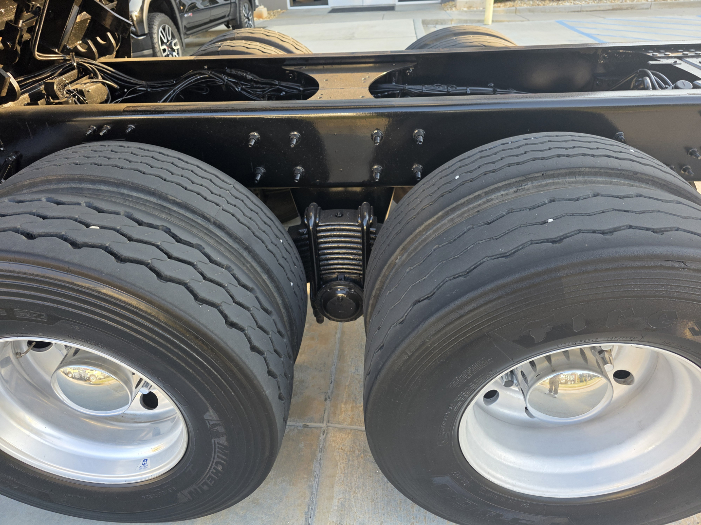 Twin rear axles of a Mack Granite dump truck showing dual tires and suspension leaf springs.