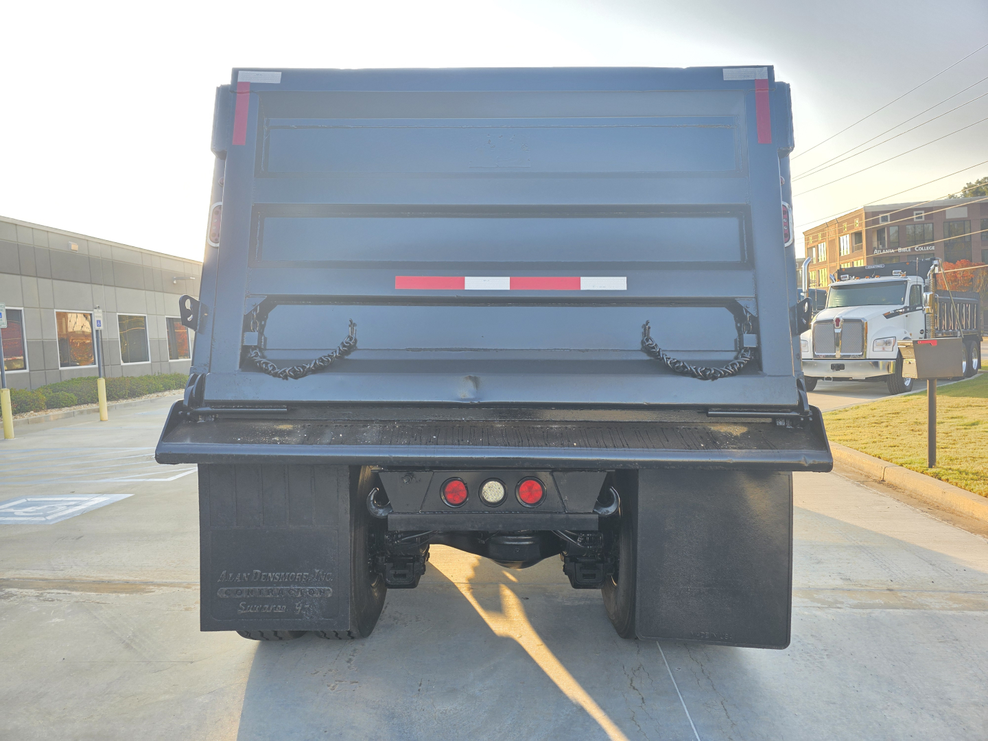 Rear view of a blue Mack Granite dump truck in a parking lot showing the tailgate, bumper, and dual rear tires with mud flaps.