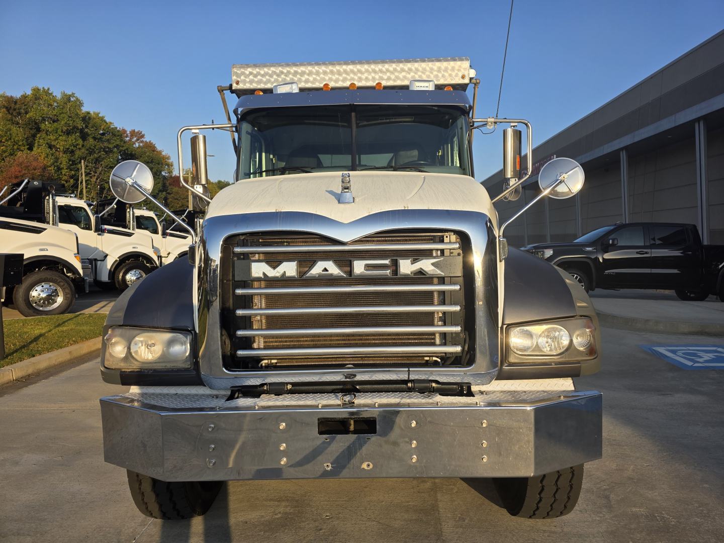 Truck front view of a 2022 Mack GRANITE dump truck showing bold chrome grille and bumper, large round mirrors, and headlamps.