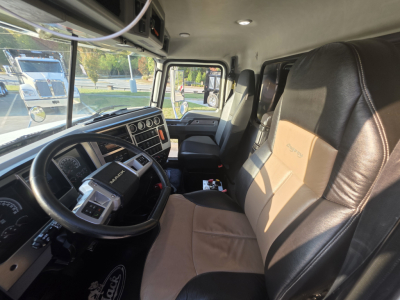 Cab interior of a 2022 Mack Granite dump truck showing steering wheel, dashboard, and tan leather seats.