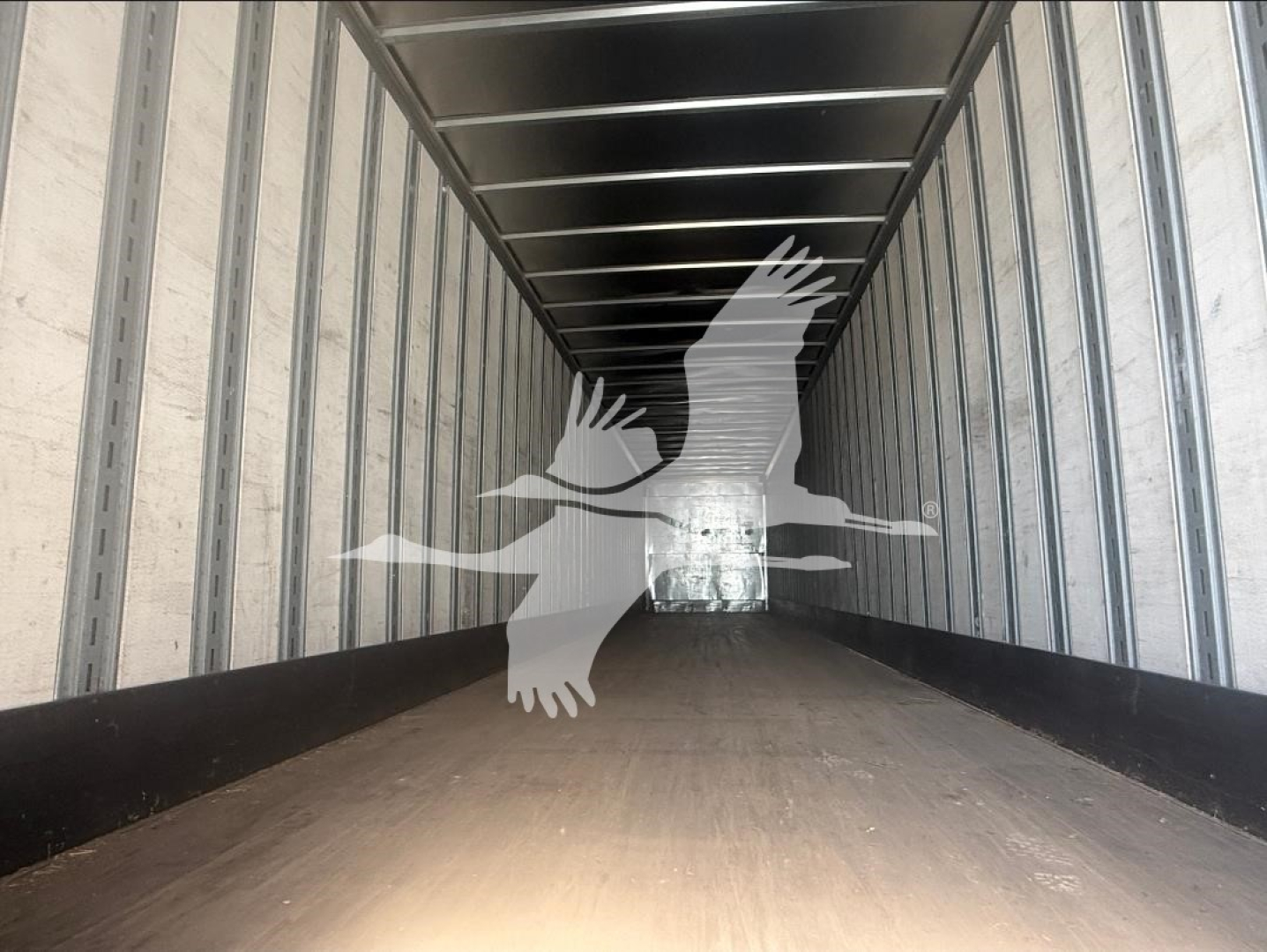 Interior of a Great Dane trailer with metal side walls and a wooden floor; watermark of a flying goose across center.