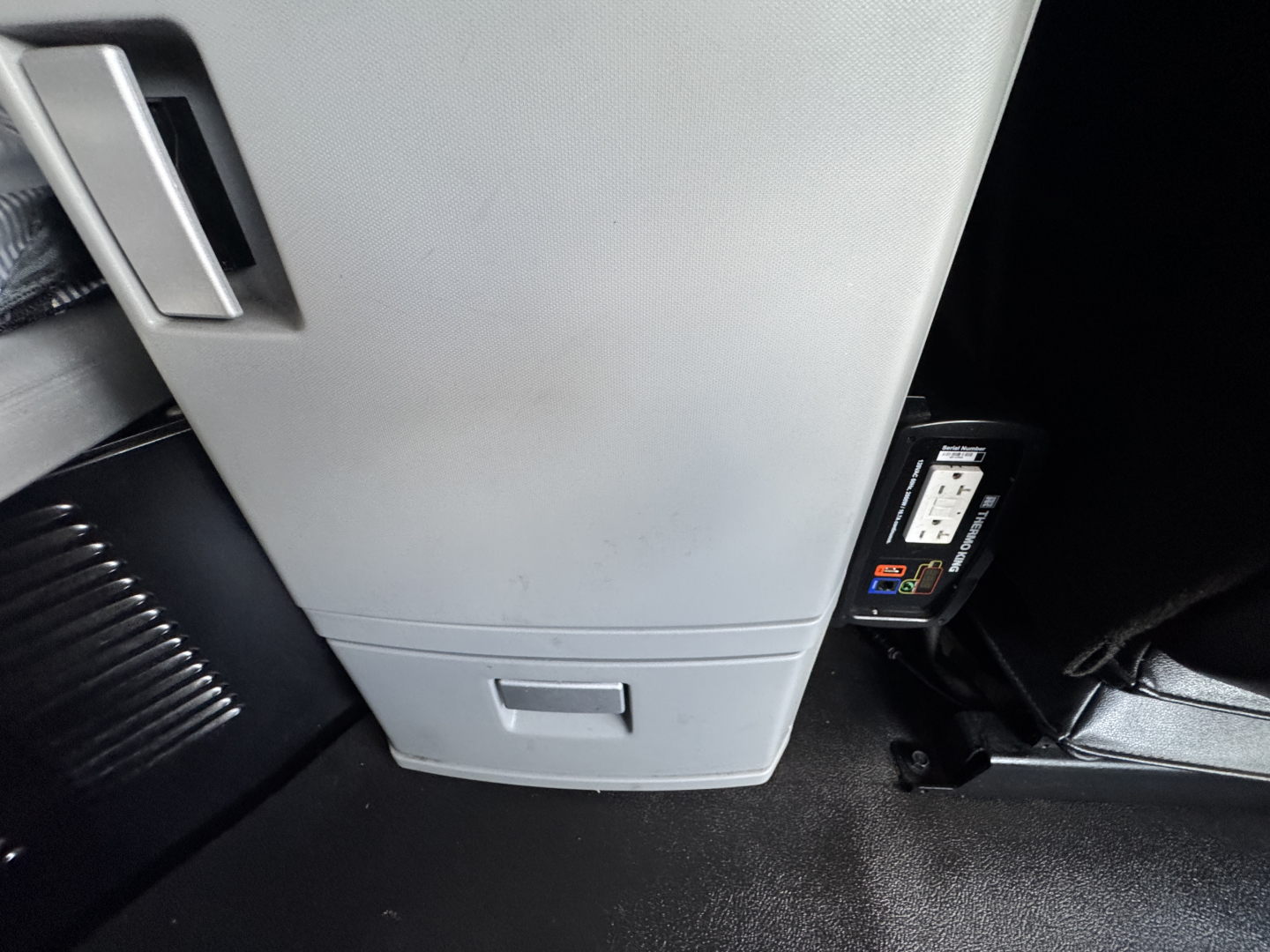 Kenworth T680 cab interior showing dashboard area and a mounted device/diagnostic reader near the entry, gray plastic center console,