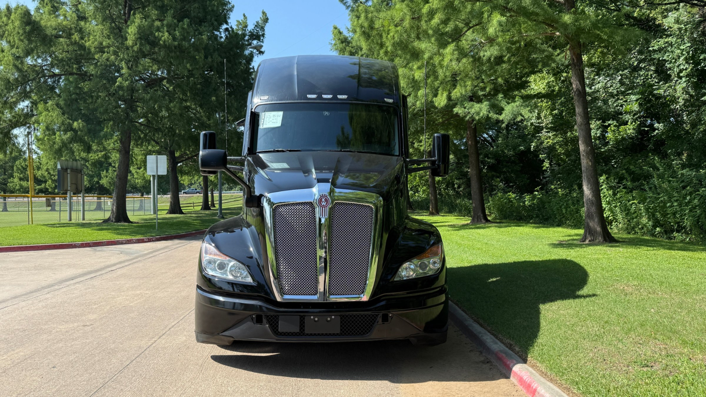 Kenworth T680 semi-truck front view showing glossy black cab and grille, headlights, large windshield, and side mirrors.