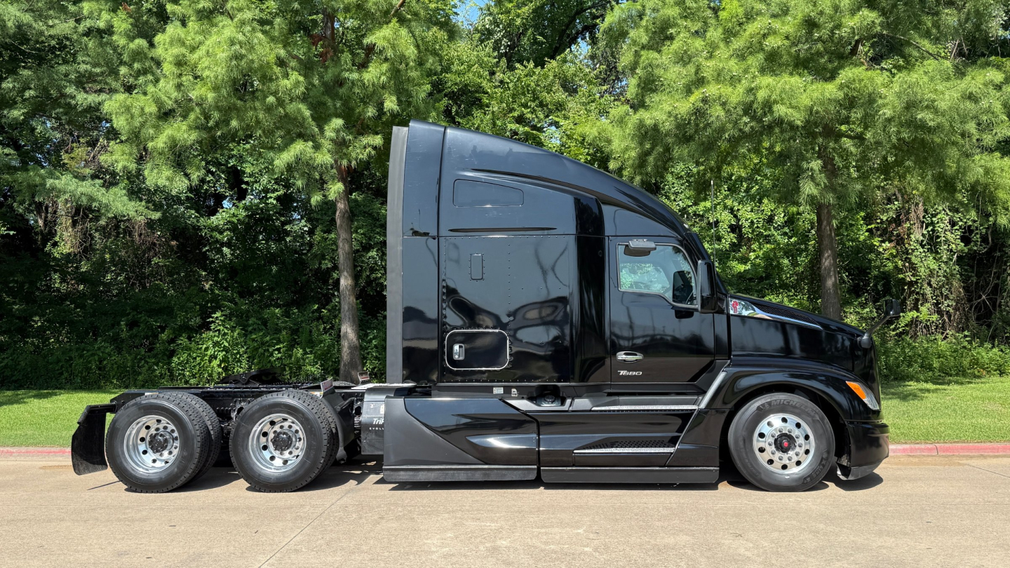 Kenworth T680 tractor side view showing sleeper cab, black paint, three axles with dual rear wheels, road tires, and fuel/air tanks visible.