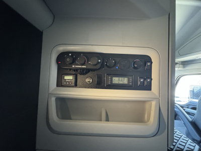 Kenworth T680 dash area showing controls and a small digital display with gauges and a radio panel.