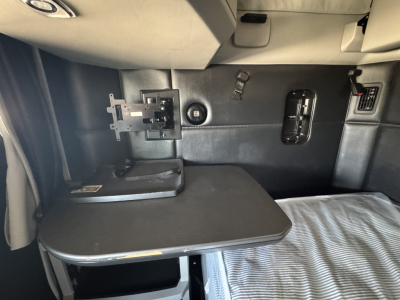 Kenworth T680 bunk area with swiveling desk/table and mounting bracket showing interior hardware and storage.