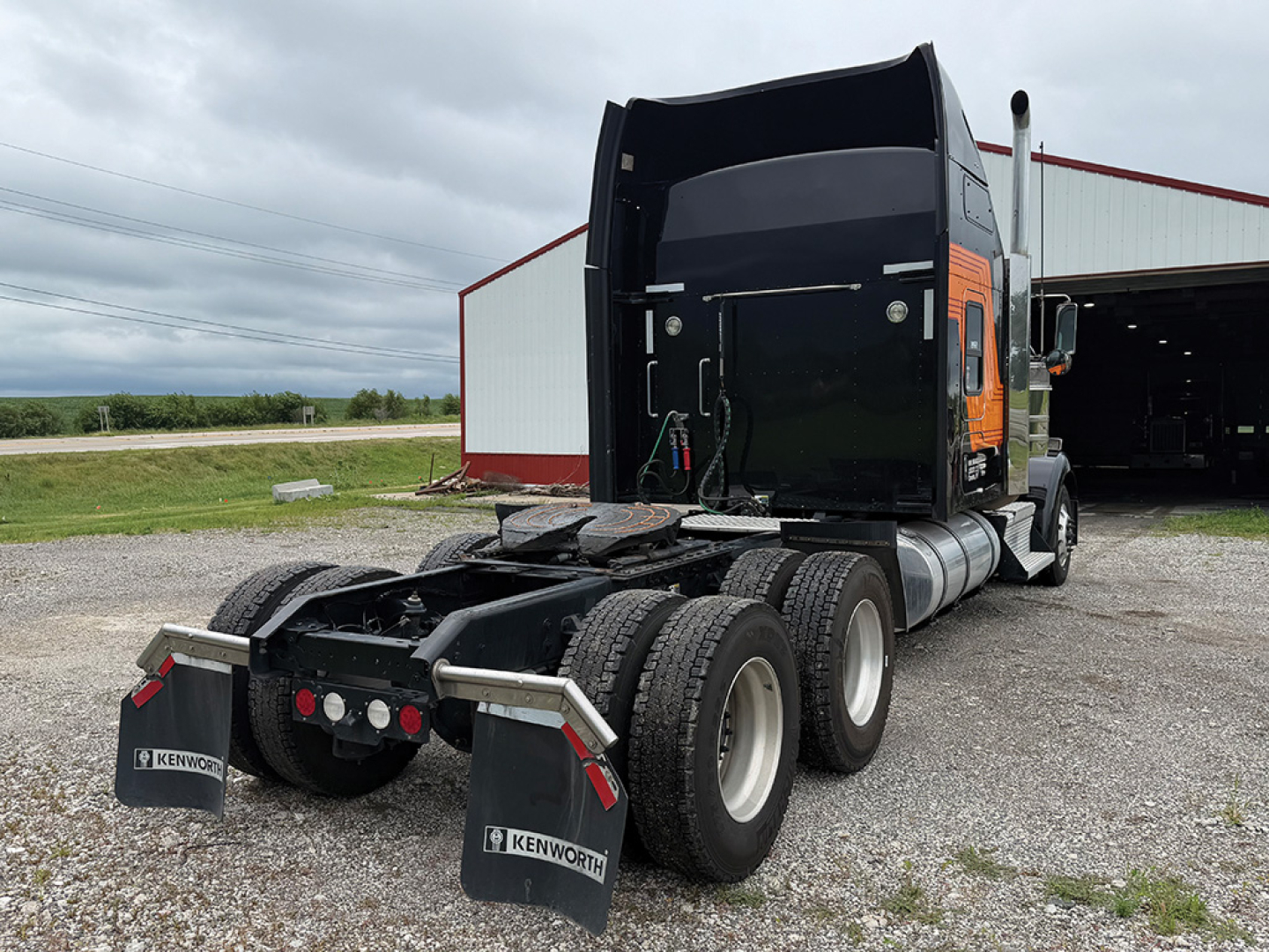 Kenworth W-900L AeroCab tractor rear view showing fifth wheel and dual rear axles with mud flaps and fuel tanks.