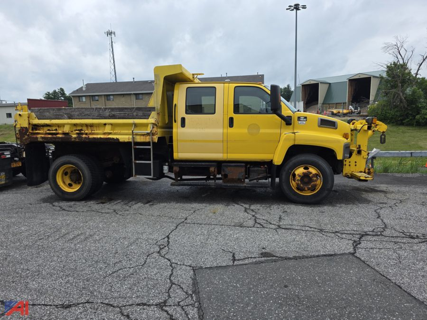 Chevrolet Kodiak C7500 dump truck side view showing yellow cab and dump bed with front-mounted equipment and dual rear wheels.