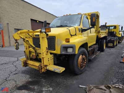 Chevrolet Kodiak C7500 dump truck with front-mounted snow plow attachment. Yellow color, cab with large side mirrors, headlights, and wheel wells.