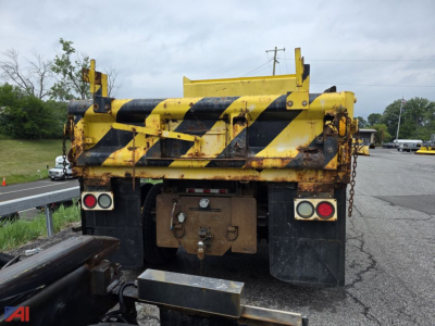Back view of a yellow and black striped dump truck bed with rear lights and towing hitch