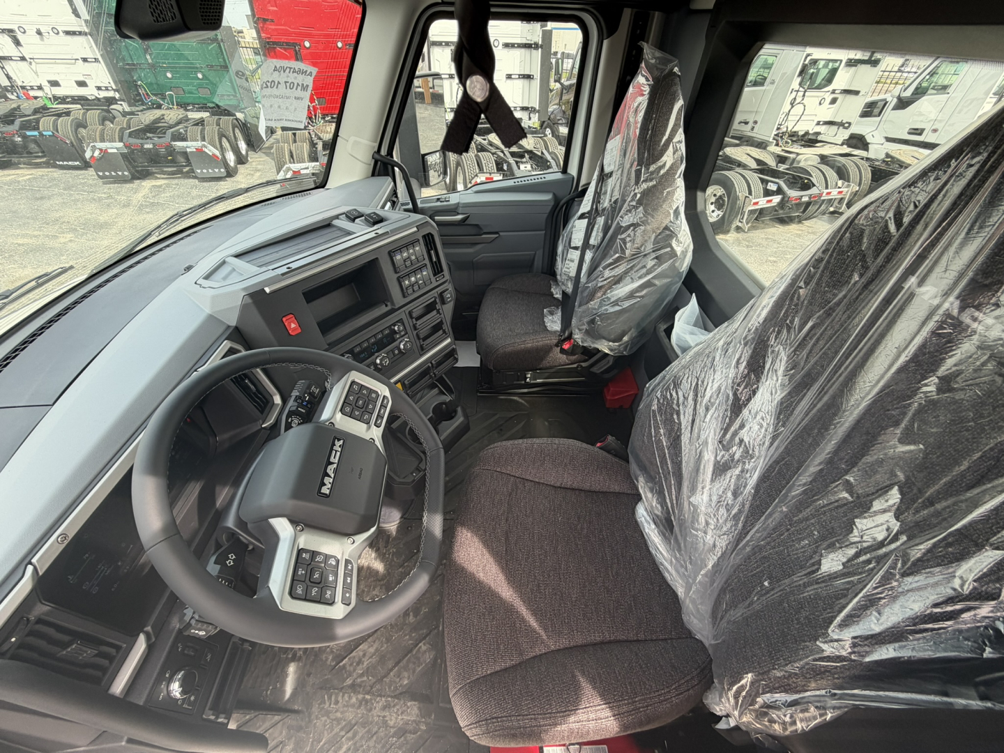 Mack AN64T cab interior showing steering wheel and dashboard with wrapped seats in plastic.