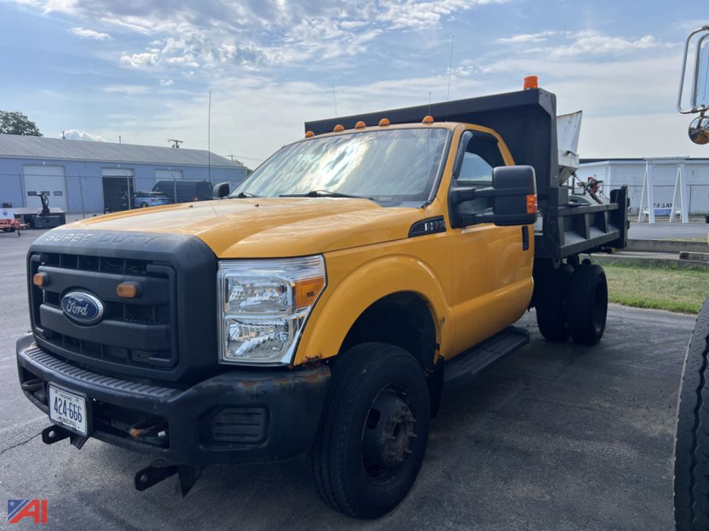 2014 Ford F-350 Super Duty dump truck with sander in orange cab and black dump bed, front view showing grille and headlights.