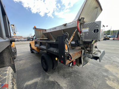 Dump truck bed with sander unit mounted at rear, side view showing hydraulic system and steel frame, under clear sky.