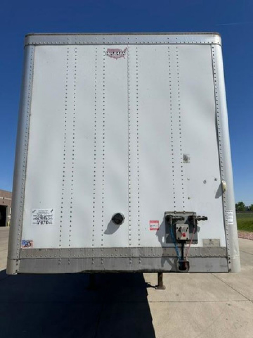 Rear view of a white 2016 Wabash van trailer with riveted metal panels, light reflector, and back door hardware visible.