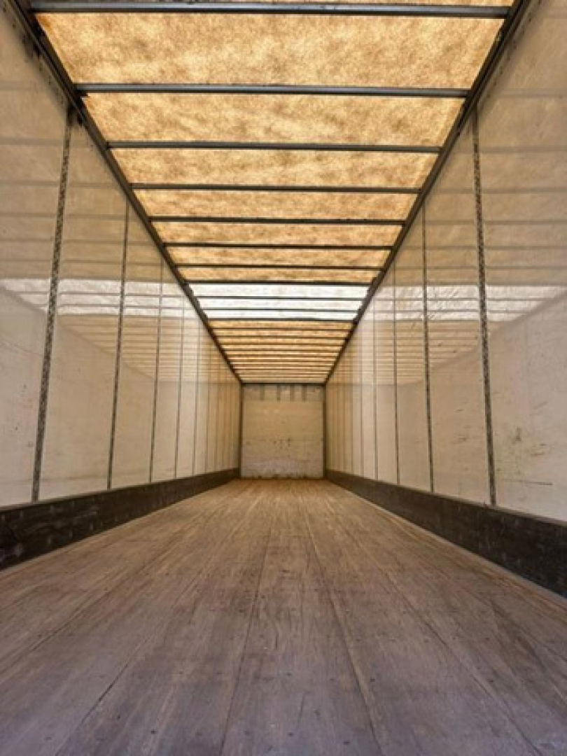 Inside of a 2016 Wabash van trailer showing wooden flooring and translucent roof panels, long empty cargo space.