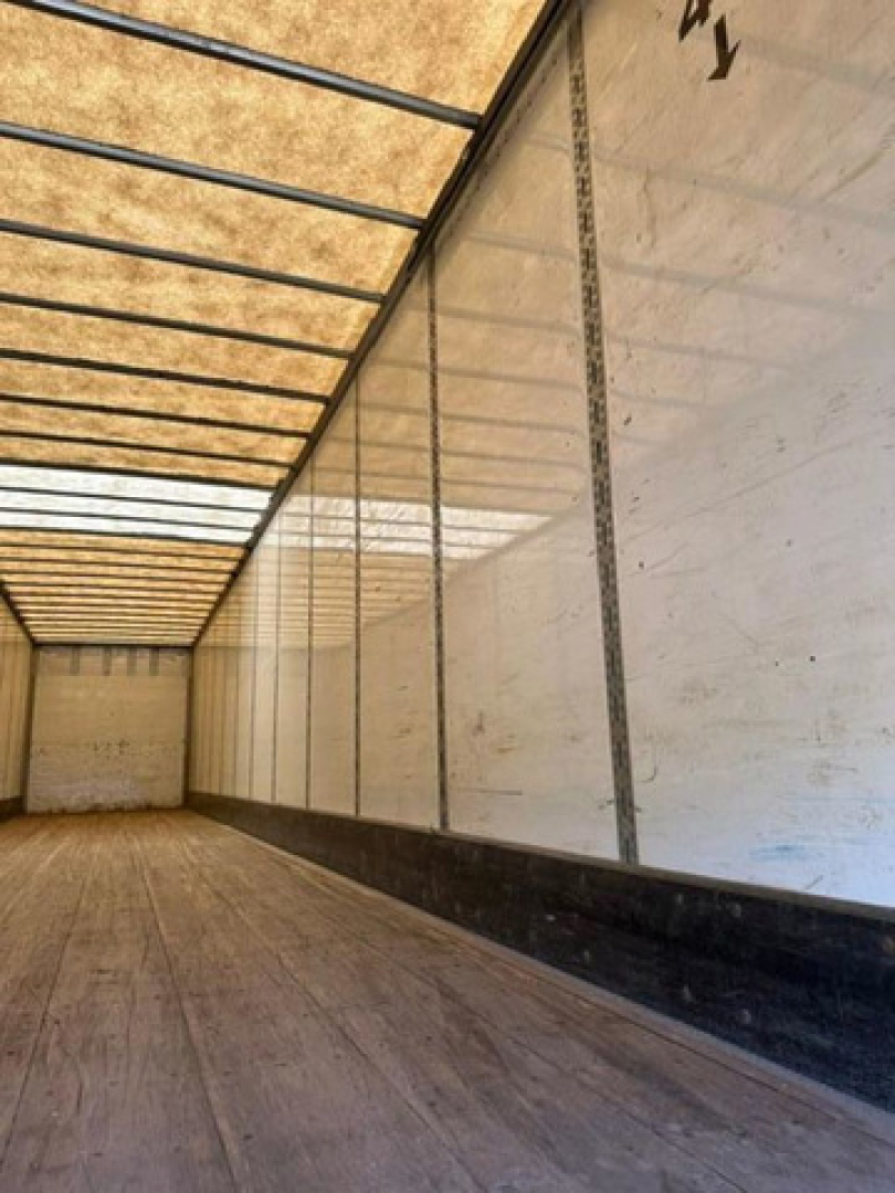 Trailer interior showing wooden floor and white sidewalls with vertical rails and load area in a Wabash van.